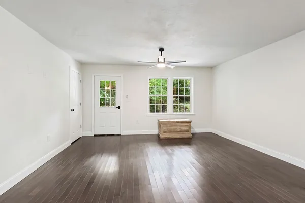 an empty room with wooden floor and windows