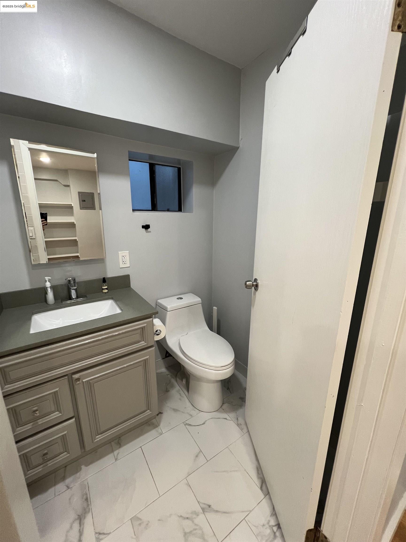 900 Everett Avenue, Unit A Oakland, CA 94602 - Photo 5 of 10 a bathroom with a toilet a sink and a mirror