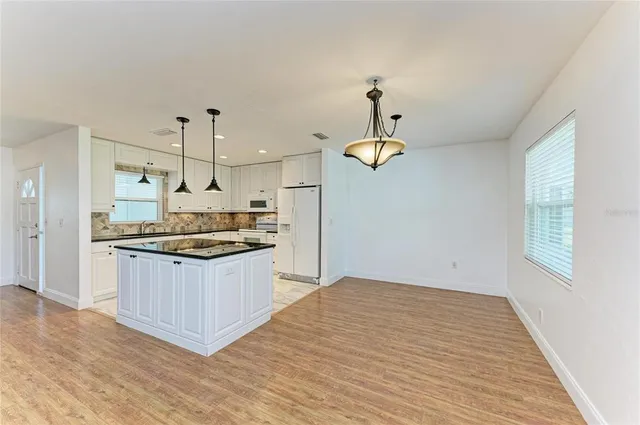 a large kitchen with stainless steel appliances granite countertop a sink a stove a refrigerator cabinets and wooden floor