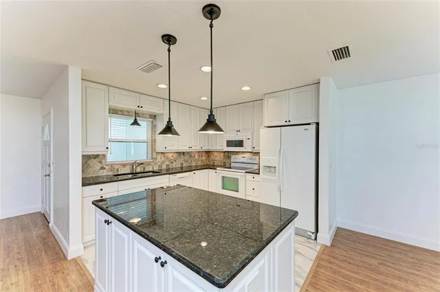 a kitchen with stainless steel appliances granite countertop a sink a refrigerator and a stove