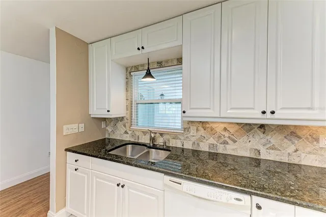 a kitchen with granite countertop white cabinets and sink