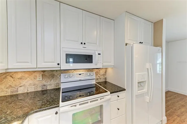a kitchen with white cabinets and white appliances
