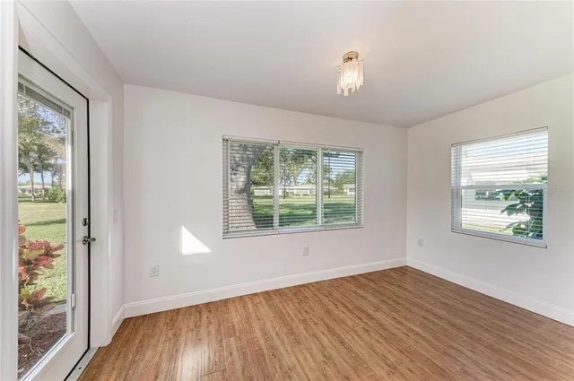 a view of an empty room with a window and wooden floor