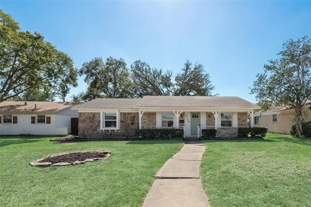 a front view of a house with a garden and trees