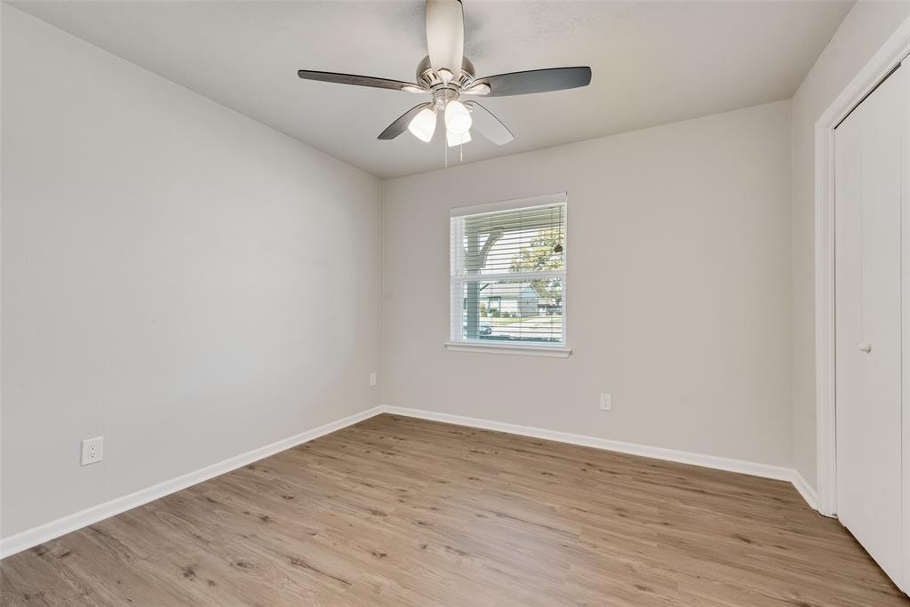 4010 Burning Tree Lane Garland, TX 75042 - Photo 17 of 20 an empty room with wooden floor chandelier fan and windows