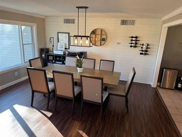 a kitchen with stainless steel appliances granite countertop a sink dishwasher a stove a dining table and chairs with wooden floor