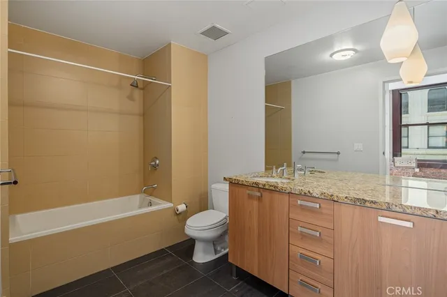 a bathroom with a granite countertop bathtub shower sink vanity mirror and toilet