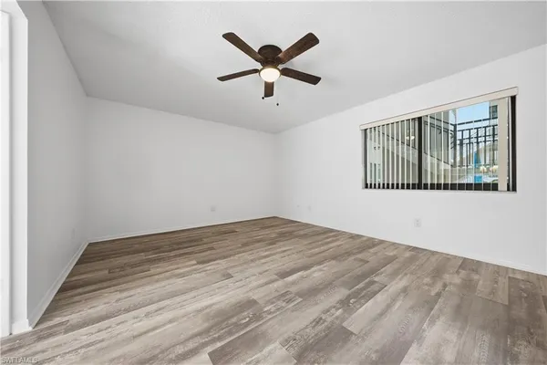 an empty room with wooden floor ceiling fan and windows