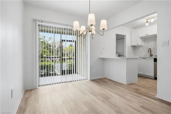 a view of a hallway with wooden floor and chandelier
