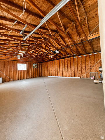 1766 Kenilworth Road Spring Glen, UT 84526 - Photo 17 of 24 Spacious garage featuring exposed wood trusses, wood-paneled walls, a concrete floor, and natural light from a single window