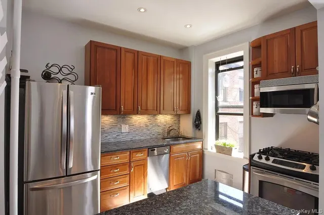 a kitchen with granite countertop a refrigerator stove and microwave