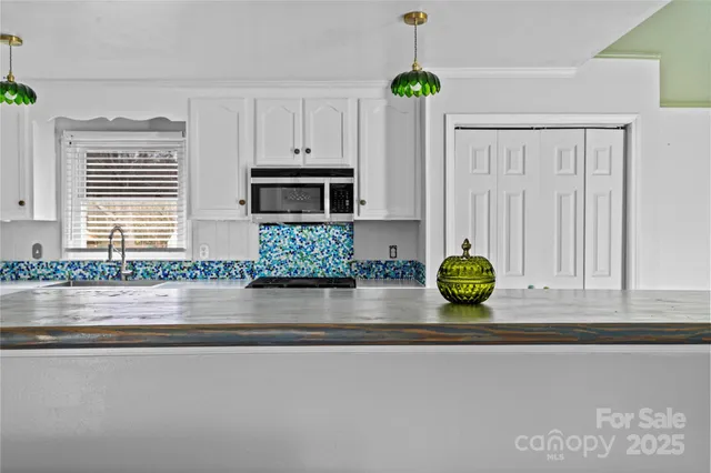 a kitchen with kitchen island granite countertop a sink a stove and a window