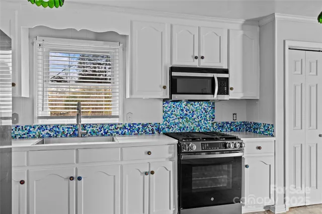a kitchen with granite countertop white cabinets and a stove top oven