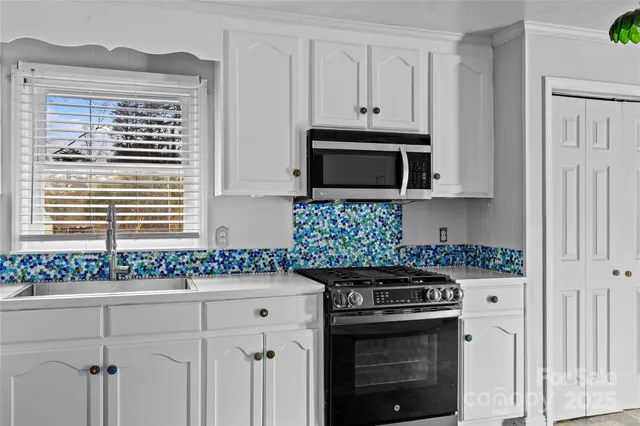 a kitchen with granite countertop white cabinets and stainless steel appliances