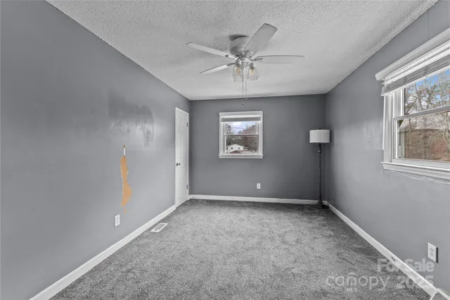 an empty room with windows and fan