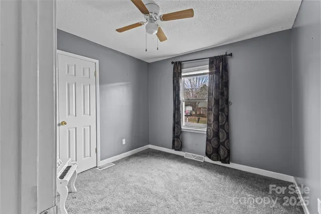 an empty room with a window and a fan