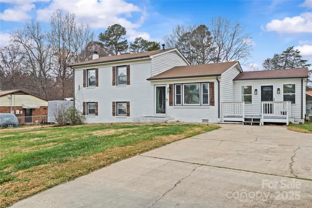 a view of a house with a yard and large tree