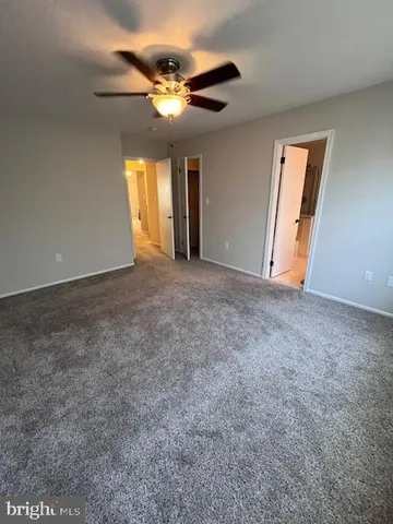 a view of an empty room with window and chandelier fan