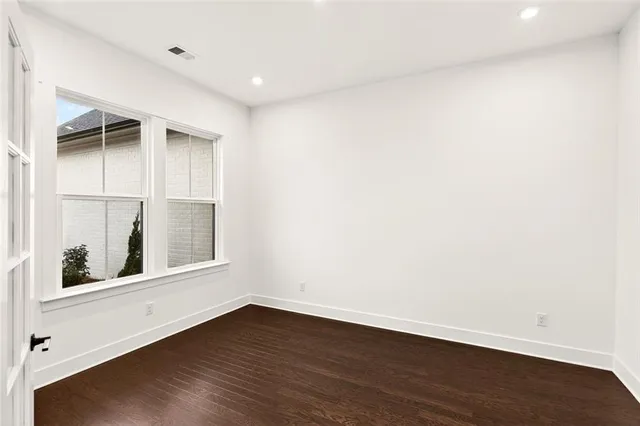 a large white kitchen with stainless steel appliances granite countertop a stove a sink a refrigerator and white cabinets with wooden floor