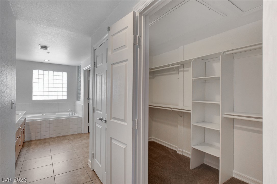230 East Flamingo Road, Unit 404 Las Vegas, NV 89169 - Photo 21 of 34 An organized walk-in closet stands adjacent to the primary bathroom complete with a soaking tub.