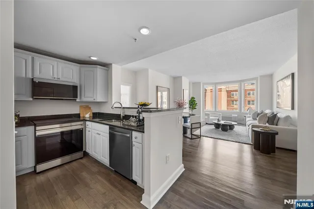 a kitchen with a stove top oven a sink dishwasher a dining table and chairs with wooden floor