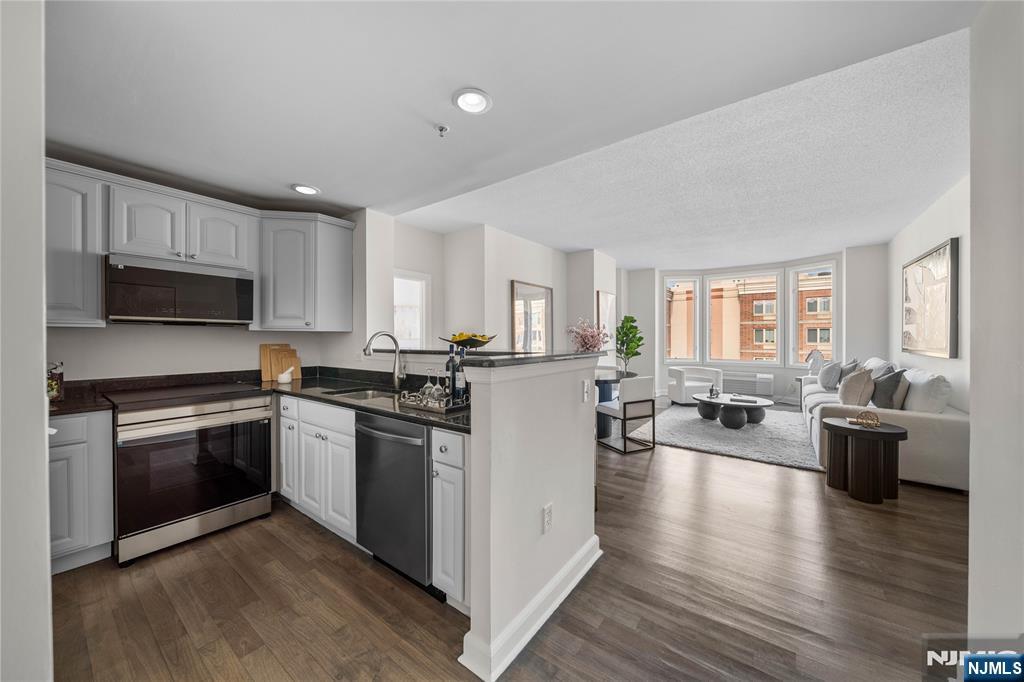 a kitchen with a stove top oven a sink dishwasher a dining table and chairs with wooden floor