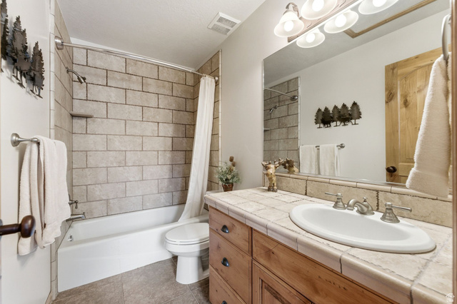 3634 North Huntsman Path, Unit C203 Eden, UT 84310 - Photo 12 of 27 Bathroom featuring a built-in wood vanity with tile countertop, integrated sink, and brushed nickel fixtures