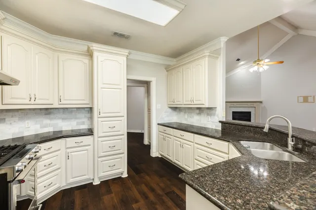 a kitchen with granite countertop a stove a sink and a refrigerator