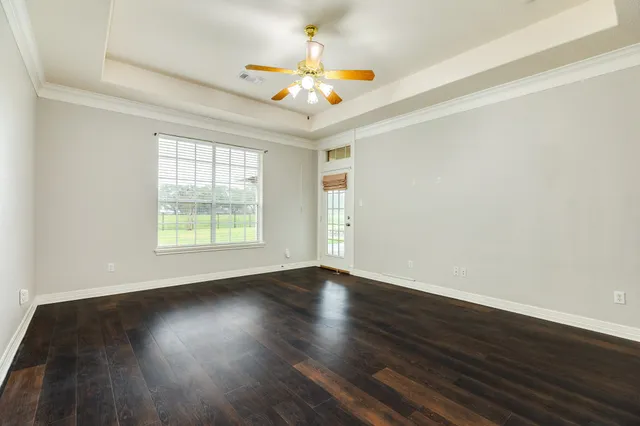 a view of an empty room with wooden floor and a chandelier