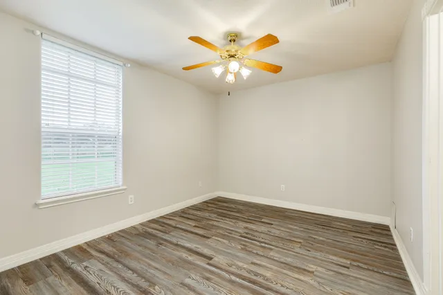 an empty room with a window and a ceiling fan