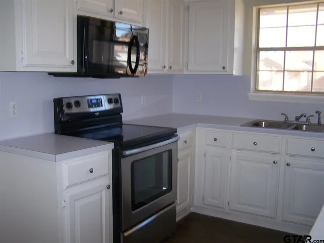 a kitchen with white cabinets and black appliances