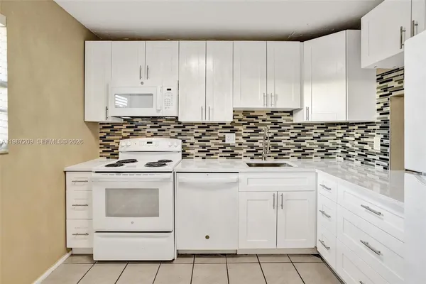 a kitchen with white cabinets and white appliances