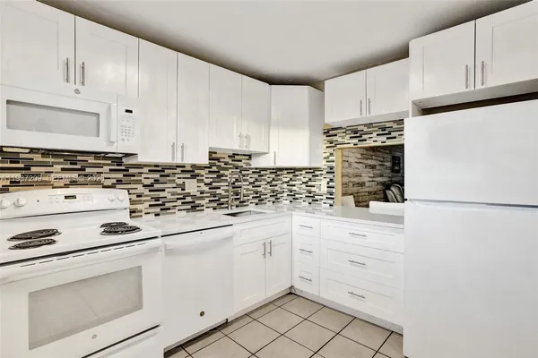 a kitchen with white cabinets and white appliances