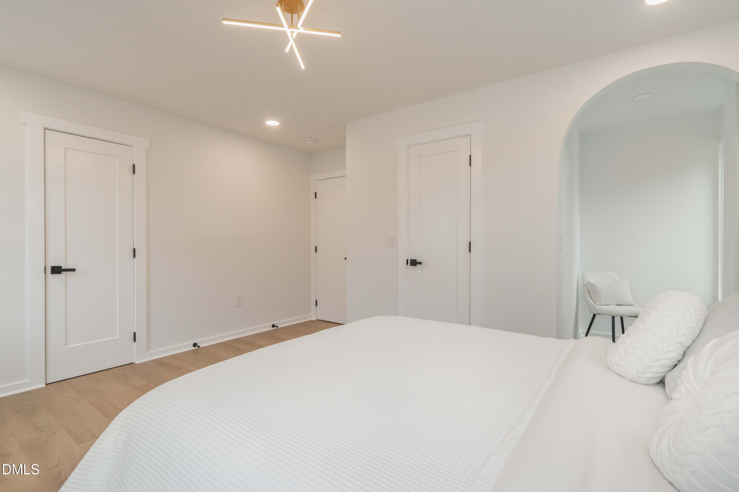 721 Currituck Drive Raleigh, NC 27609 - Photo 43 of 81 a bedroom with a white bed and a chandelier