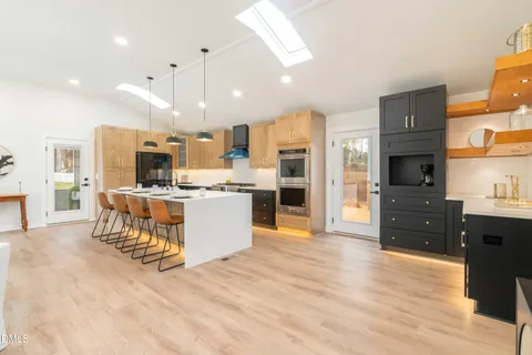 a kitchen with a sink a stove and a dining table with chandelier