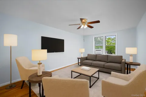 a living room with furniture a flat screen tv and a window