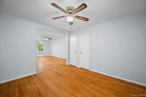 an empty room with wooden floor and ceiling fan