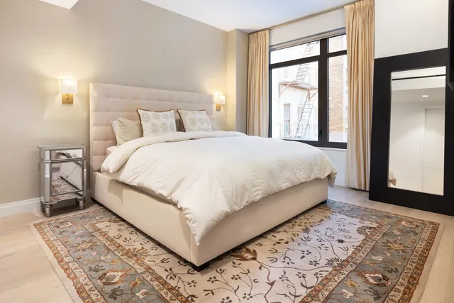 a large bed sitting in a bedroom next to a window