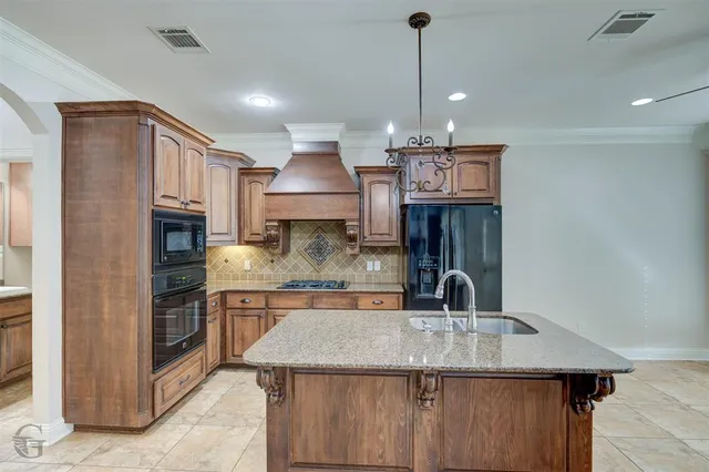 a kitchen with kitchen island granite countertop a sink and a stove