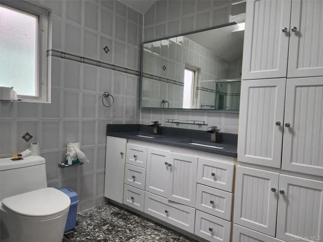 a bathroom with a granite countertop sink a toilet and a shower