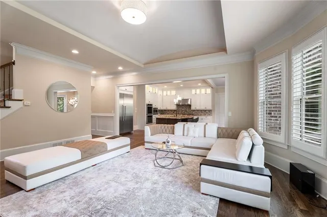a living room with couches and kitchen view with wooden floor