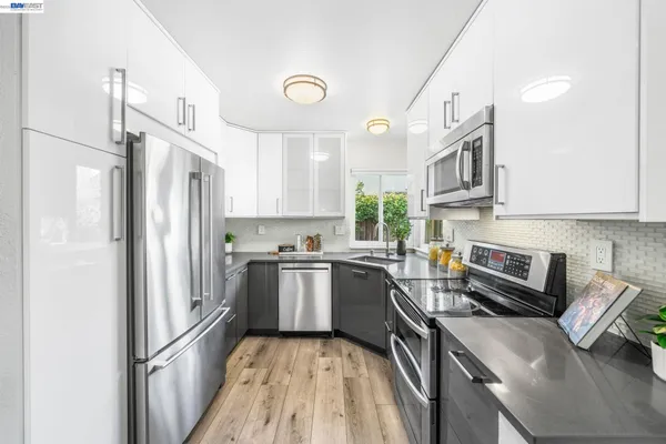 a kitchen with stainless steel appliances granite countertop a refrigerator a oven a sink a stove and white cabinets
