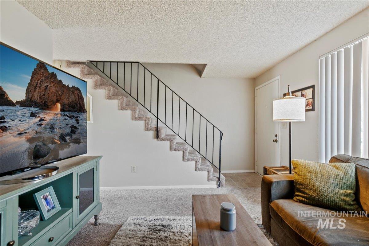 819 North Benjamin Lane Boise, ID 83704 - Photo 3 of 26 Carpeted living room featuring a textured ceiling and stairway