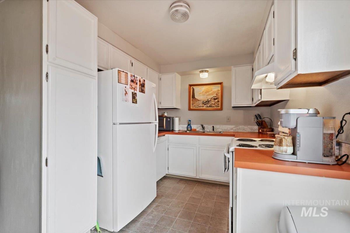 819 North Benjamin Lane Boise, ID 83704 - Photo 6 of 26 Kitchen with white appliances, white cabinets, light countertops, and under cabinet range hood