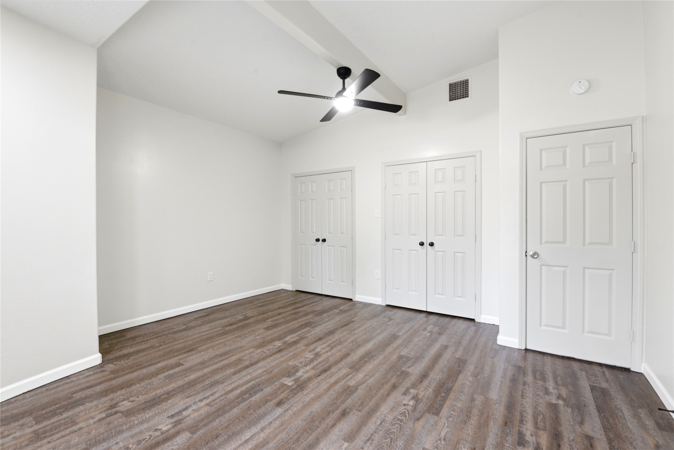 9403 Spaulding Street Houston, TX 77016 - Photo 20 of 50 This room features a high ceiling with a modern ceiling fan, two closets with double doors, and sleek wood flooring. The neutral color palette enhances the bright and airy feel.