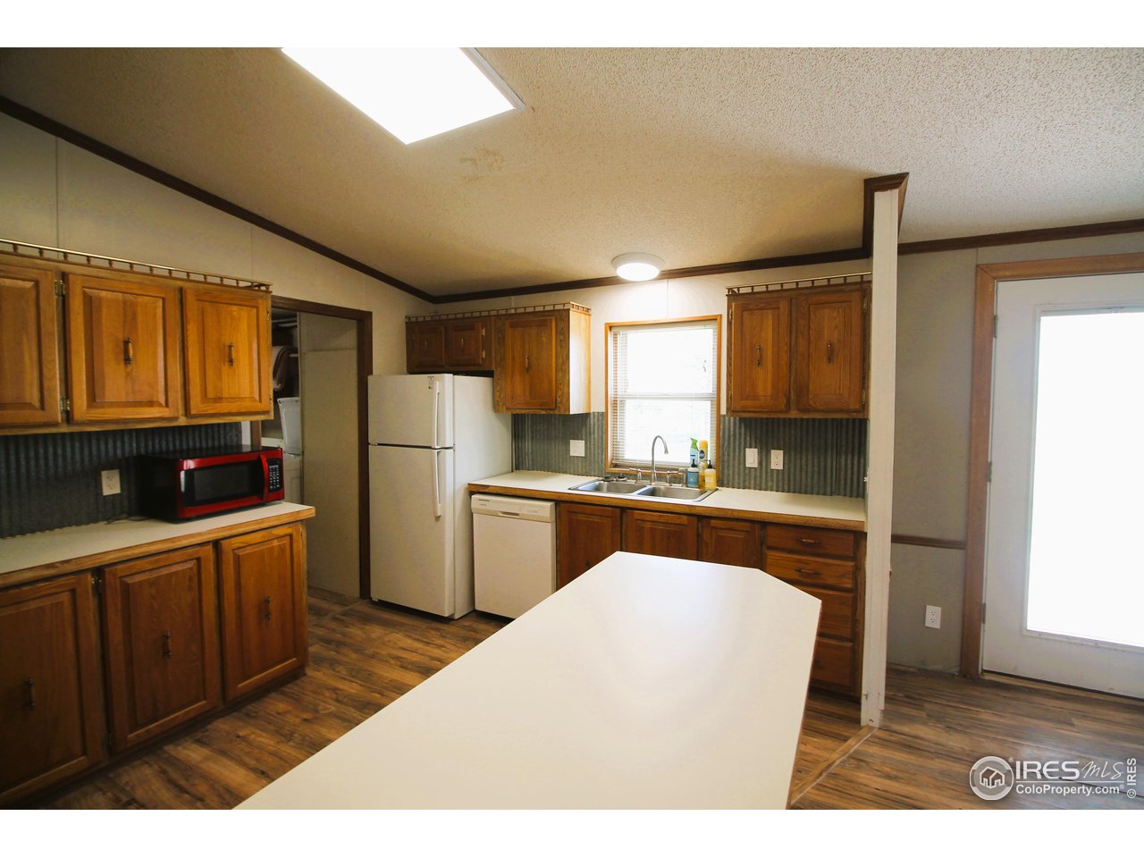 22354 County Road 41 Sterling, CO 80751 - Photo 33 of 40 a kitchen with refrigerator cabinets and wooden floor