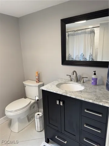 a bathroom with a granite countertop toilet sink and mirror