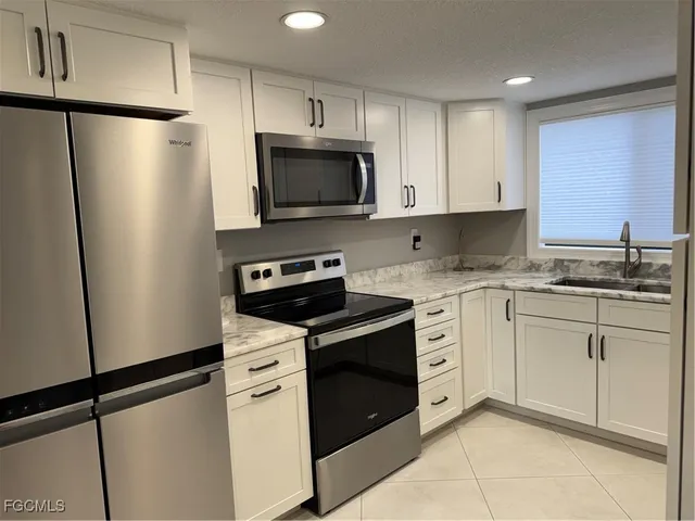 a kitchen with white cabinets white stainless steel appliances and sink