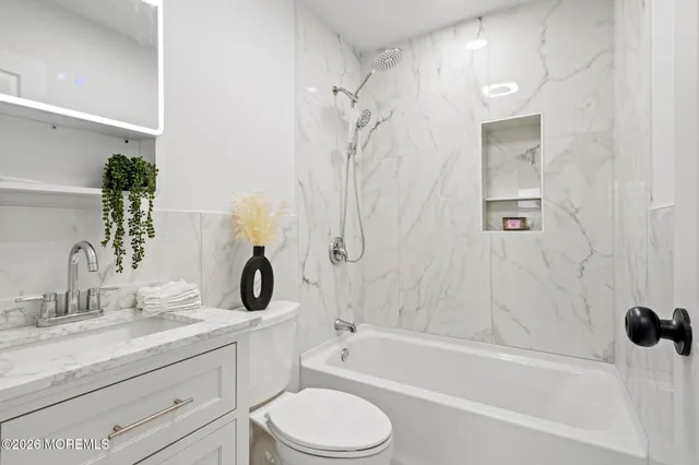 a bathroom with a granite countertop sink a toilet and shower