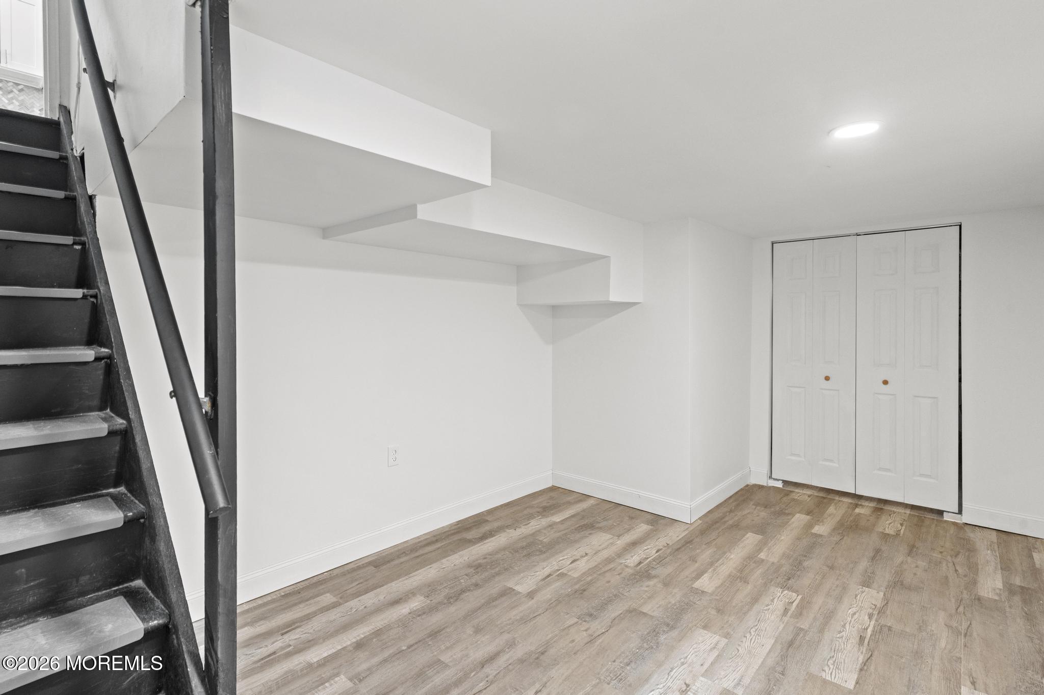 20 Kenneth Terrace Neptune Township, NJ 07753 - Photo 27 of 34 a view of an empty room with wooden floor and stairs
